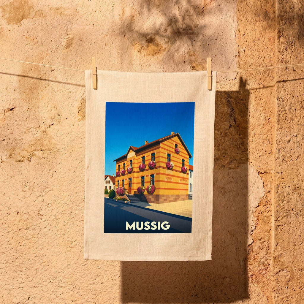 Torchon souvenir de la ville de Mussig avec une illustration stylisée d'un bâtiment fleuri.
