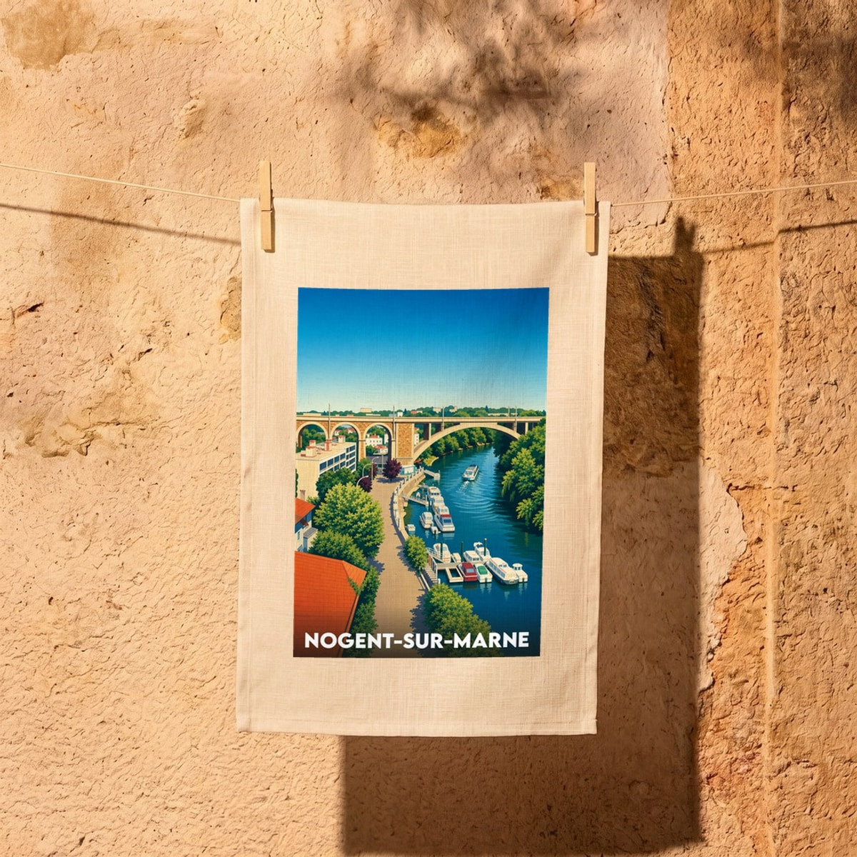 Torchon souvenir de la ville de Nogent-sur-Marne illustré d'un paysage stylisé des bords de Marne et du viaduc.