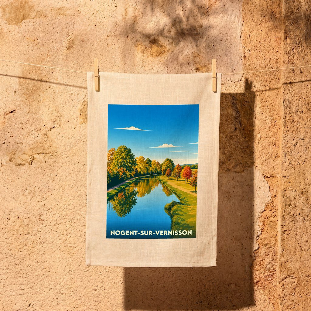 Torchon souvenir de la ville de Nogent-sur-Vernisson illustré d'un paysage de canal automnal.