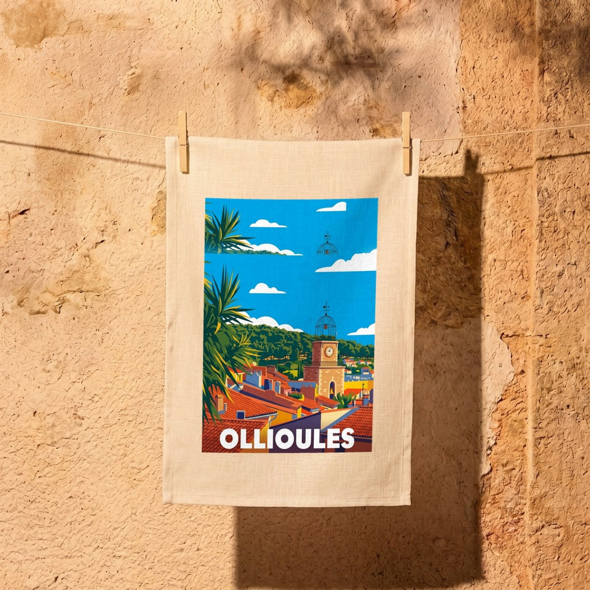 Torchon souvenir de la ville d'Ollioules avec une illustration stylisée de ses toits provençaux et de son clocher.