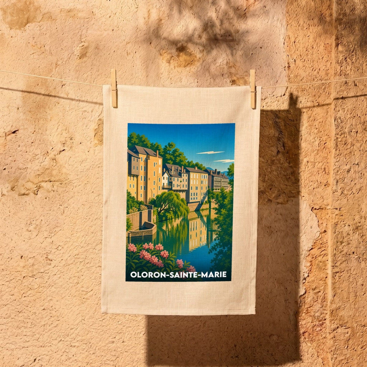 Torchon souvenir de la ville de Oloron-Sainte-Marie illustrant ses maisons typiques au bord de l'eau.