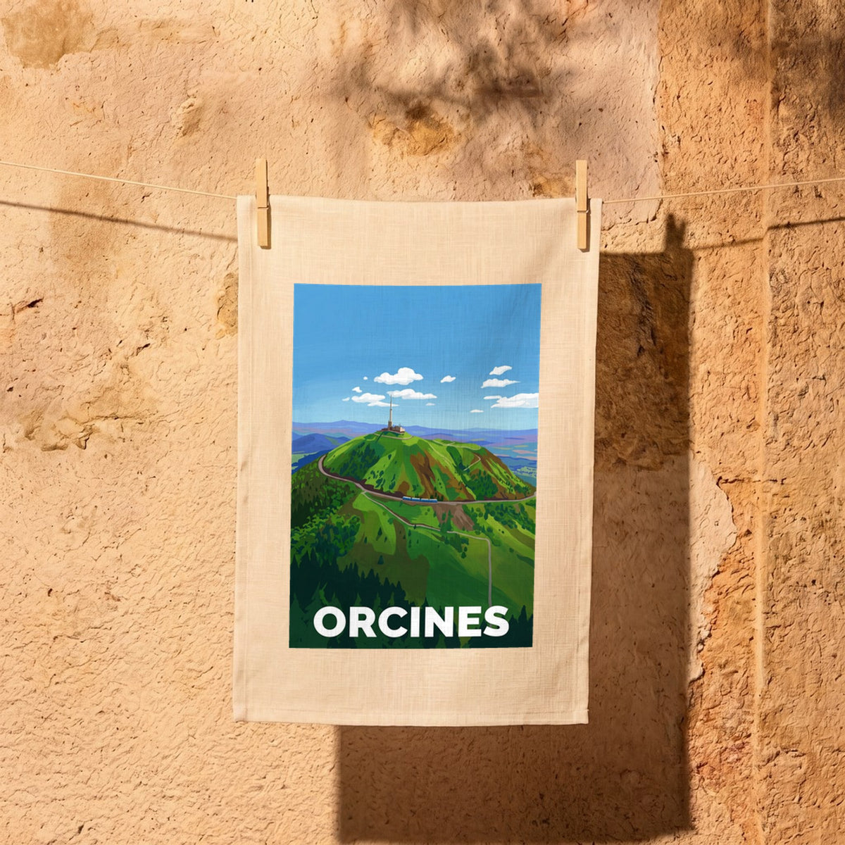 Torchon souvenir de la ville d'Orcines avec une illustration stylisée du Puy de Dôme.