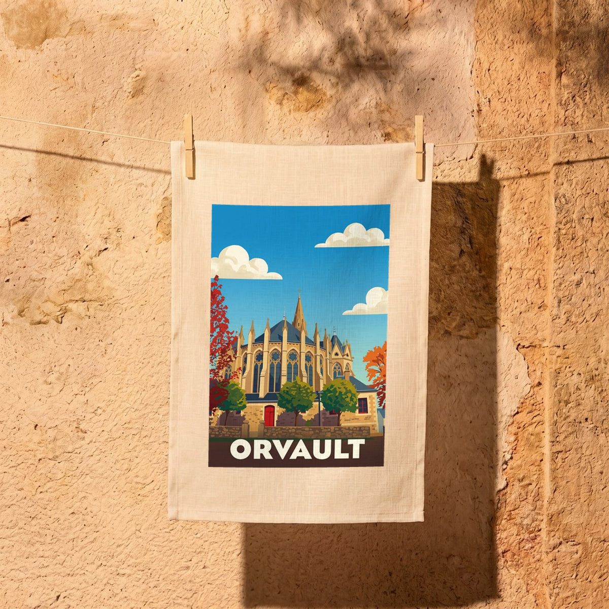 Torchon souvenir de la ville d'Orvault avec une illustration stylisée de son église entourée d'arbres aux couleurs automnales.