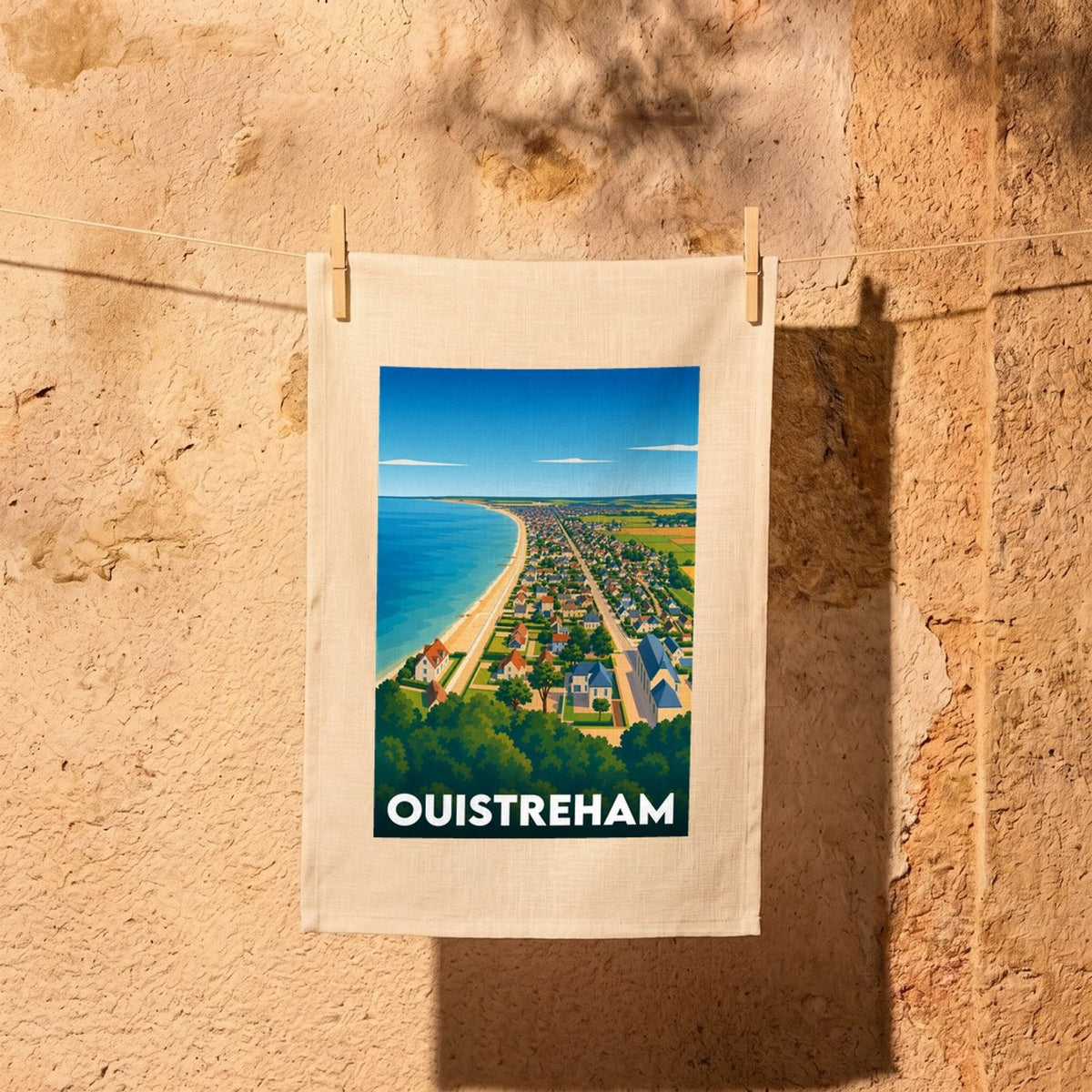 Torchon souvenir de la ville de Ouistreham avec une illustration stylisée d'une vue aérienne du littoral.