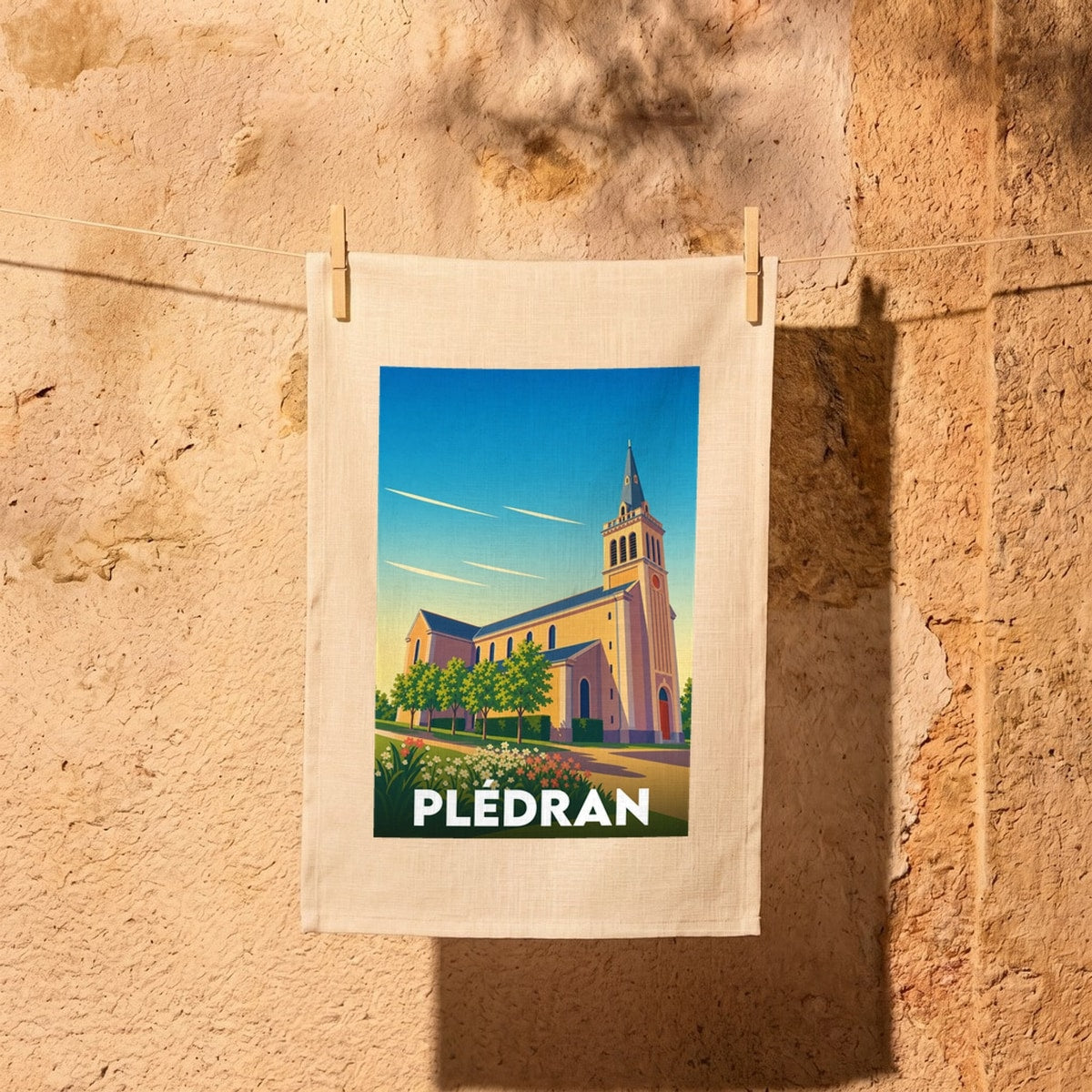 Torchon souvenir de la ville de Plédran illustré par une église stylisée sous un ciel azur.