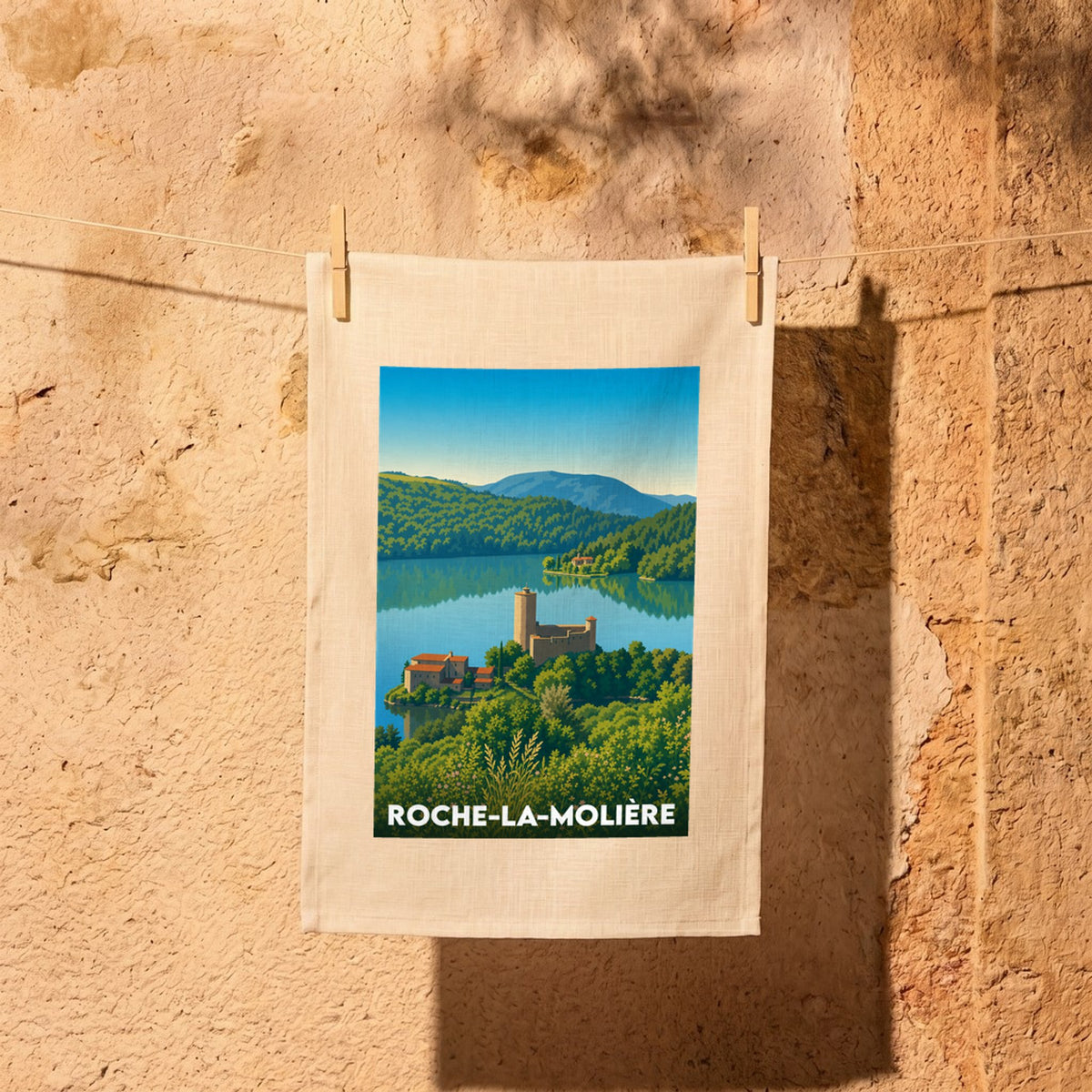 Torchon souvenir de la ville de Roche-la-Molière avec une illustration stylisée de son château au bord de l'eau.