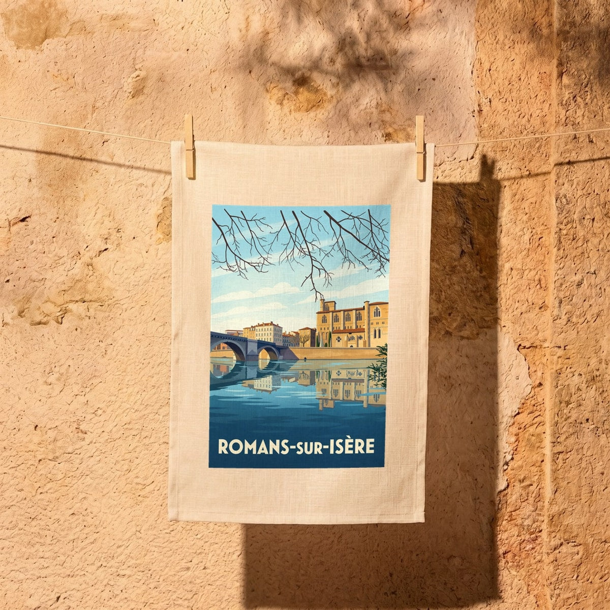 Torchon souvenir de la ville de Romans-sur-Isère avec une illustration stylisée du pont et de la collégiale en bord de rivière.
