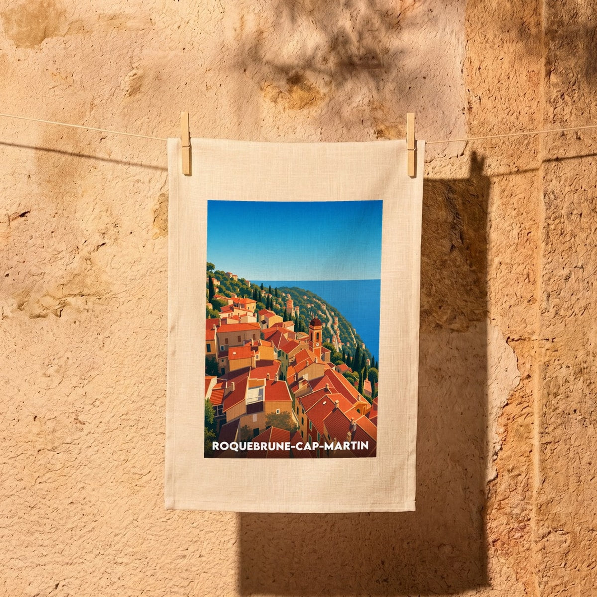 Torchon souvenir de la ville de Roquebrune-Cap-Martin orné d'une illustration stylisée du village perché en bord de mer.