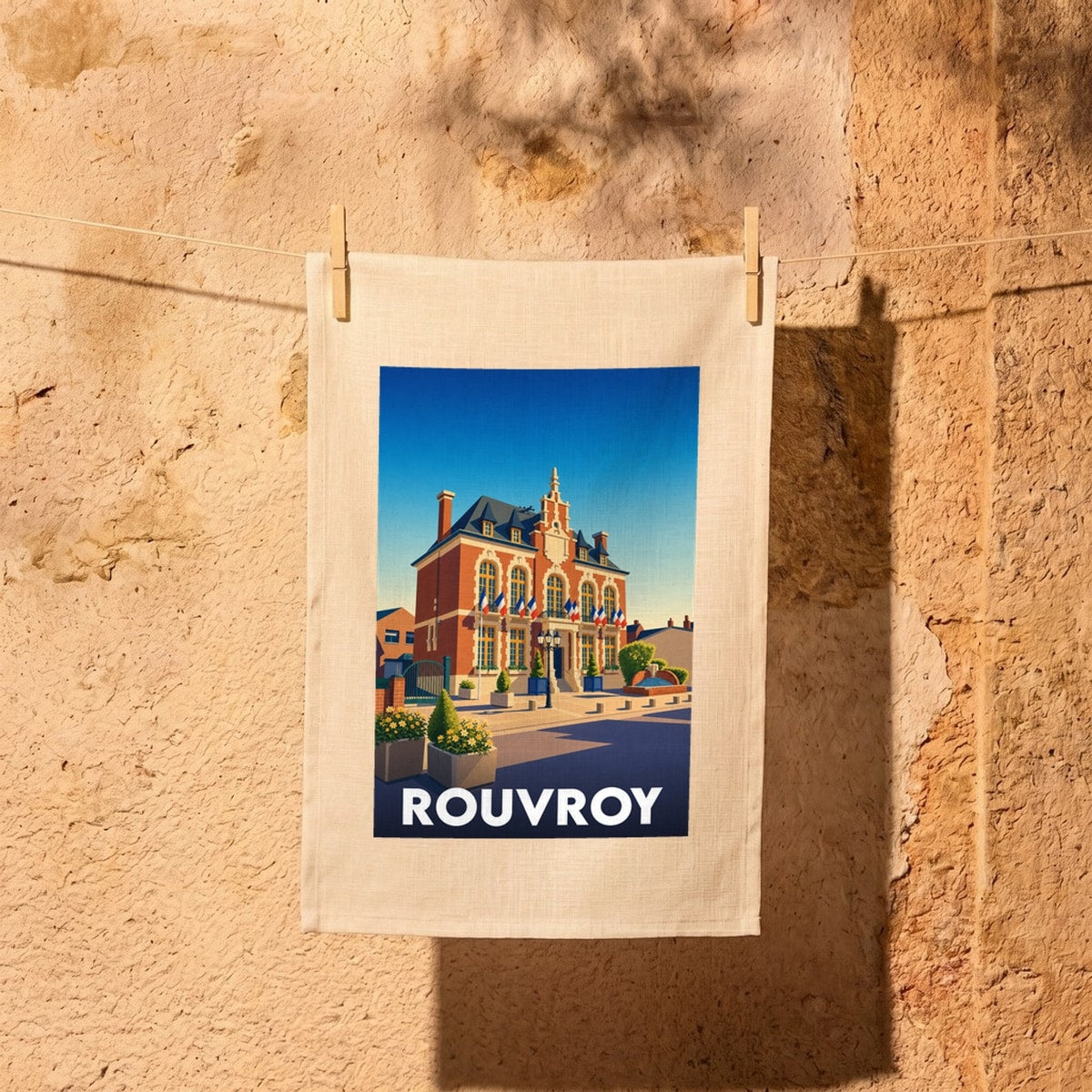 Torchon souvenir de la ville de Rouvroy avec une illustration stylisée de son hôtel de ville sous un ciel bleu.