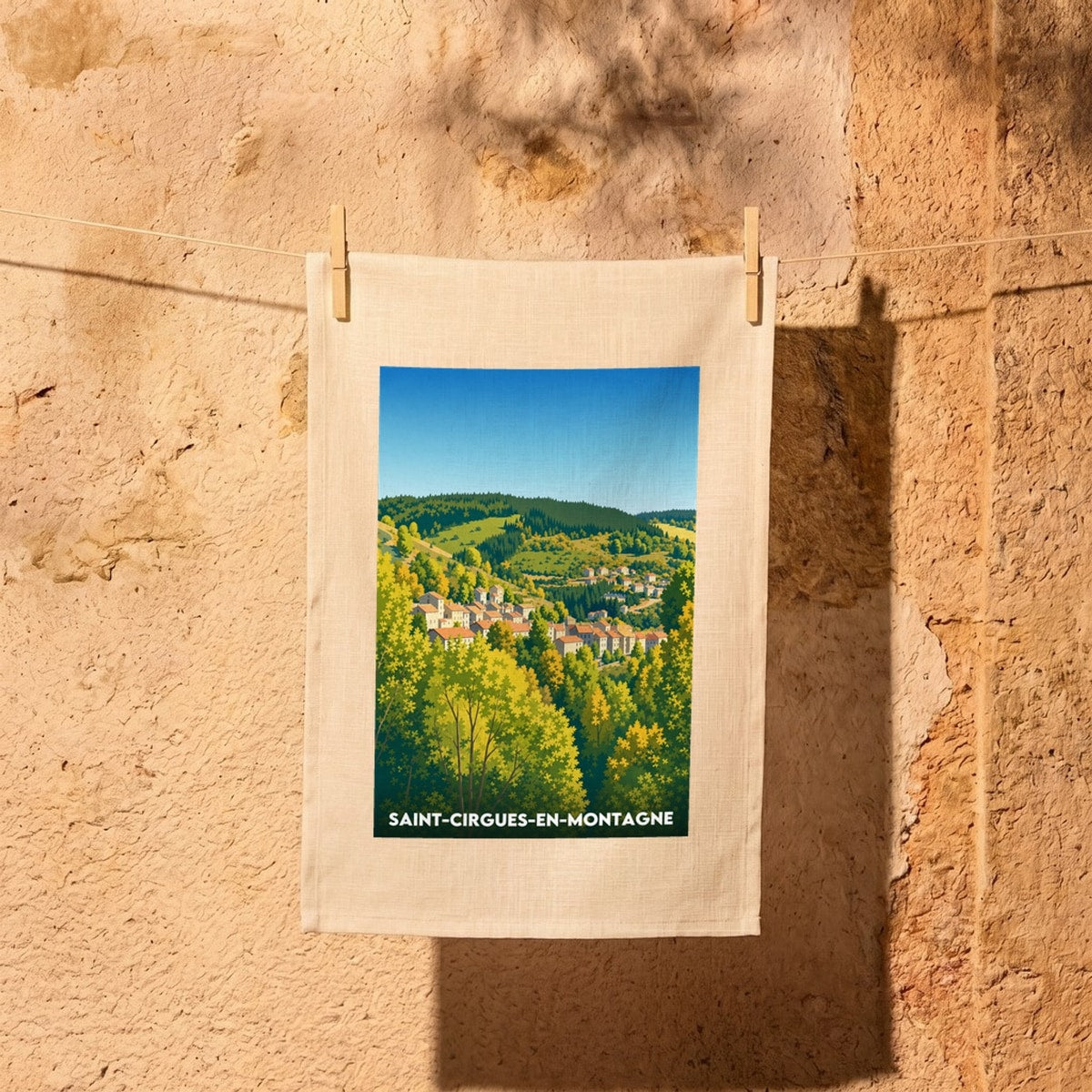 Torchon souvenir de Saint-Cirgues-en-Montagne avec une illustration stylisée du village niché dans les montagnes.