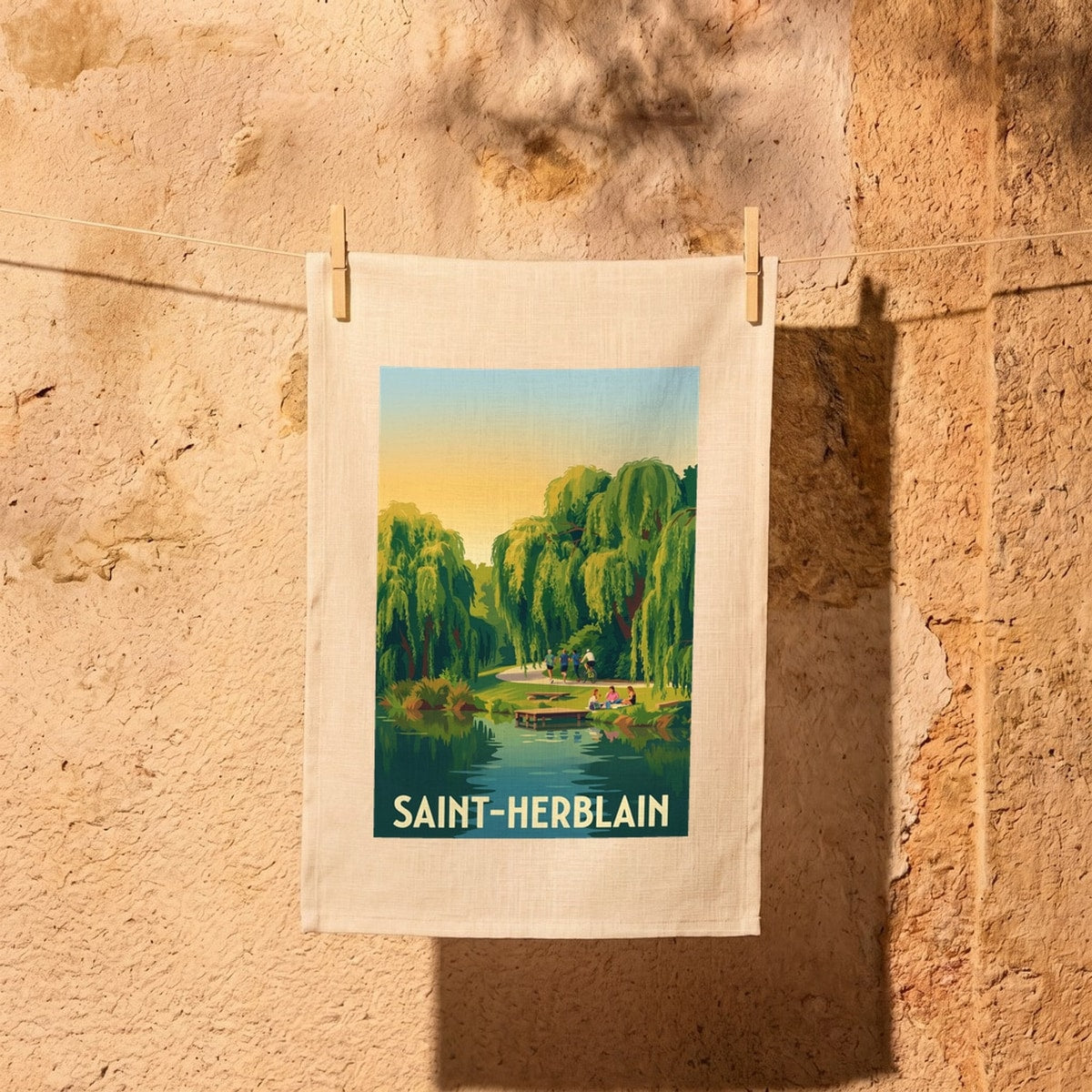 Torchon souvenir de la ville de Saint-Herblain avec une illustration stylisée d'un parc paysager au bord de l'eau.