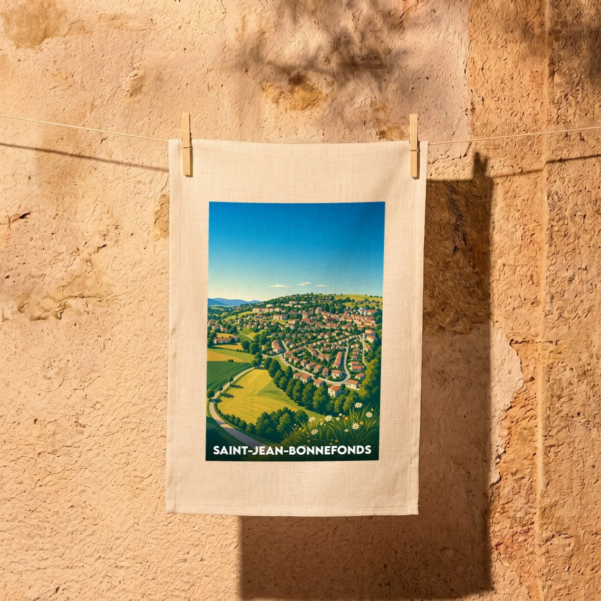 Torchon souvenir de la ville de Saint-Jean-Bonnefonds avec une illustration stylisée d'un village vallonné.