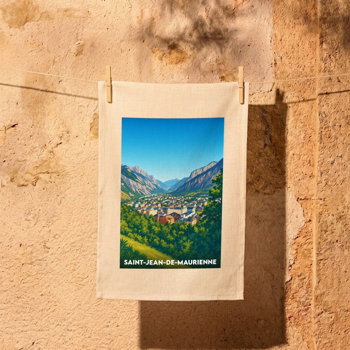 Torchon souvenir de la ville de Saint-Jean-de-Maurienne avec une illustration stylisée d'un panorama montagneux.