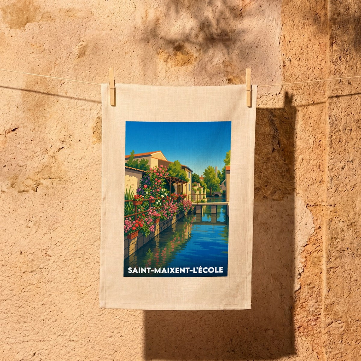 Torchon souvenir de la ville de Saint-Maixent-l'École avec une illustration colorée et bucolique représentant un canal fleuri.