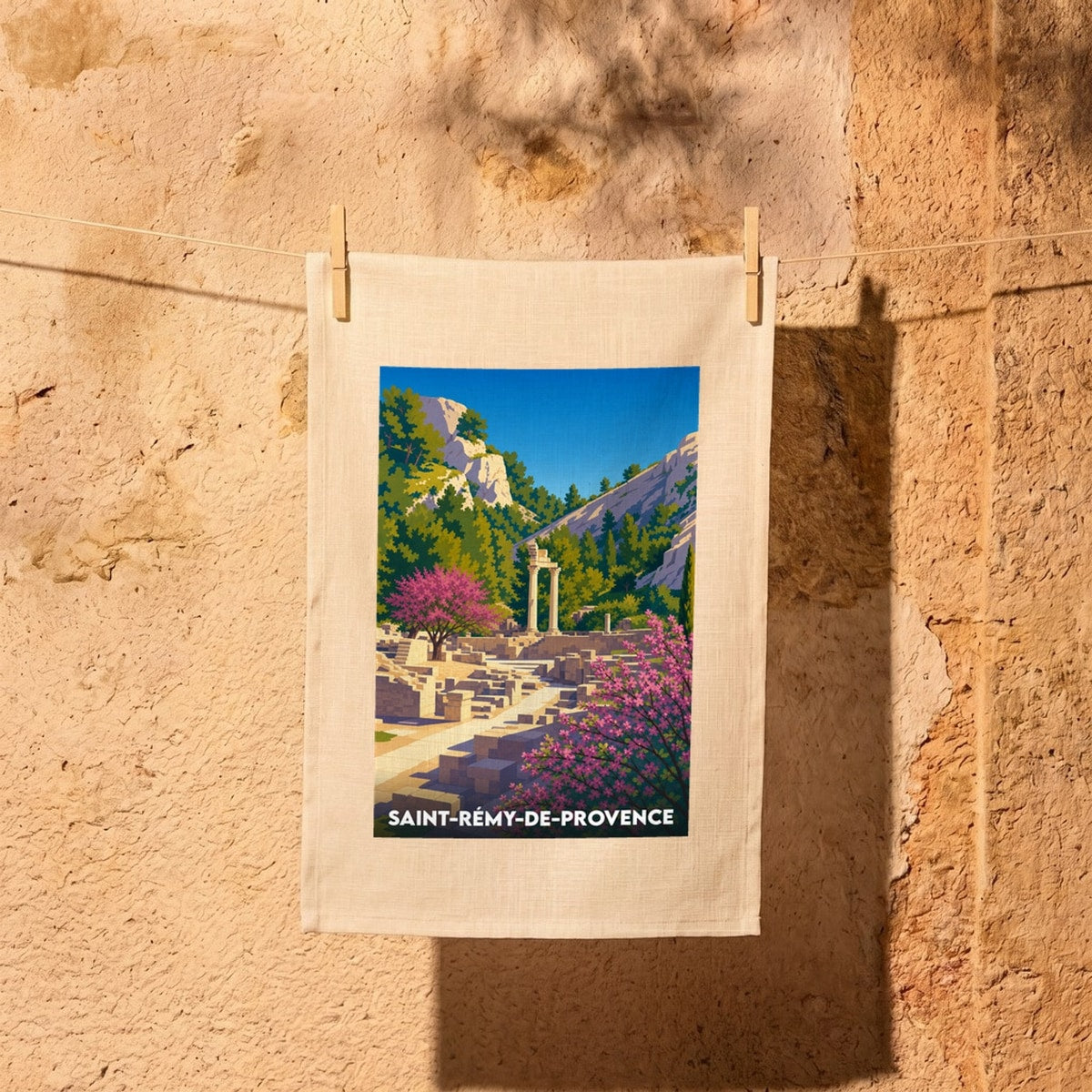 Torchon souvenir de la ville de Saint-Rémy-de-Provence illustré d'un paysage stylisé de ruines antiques dans un décor provençal.