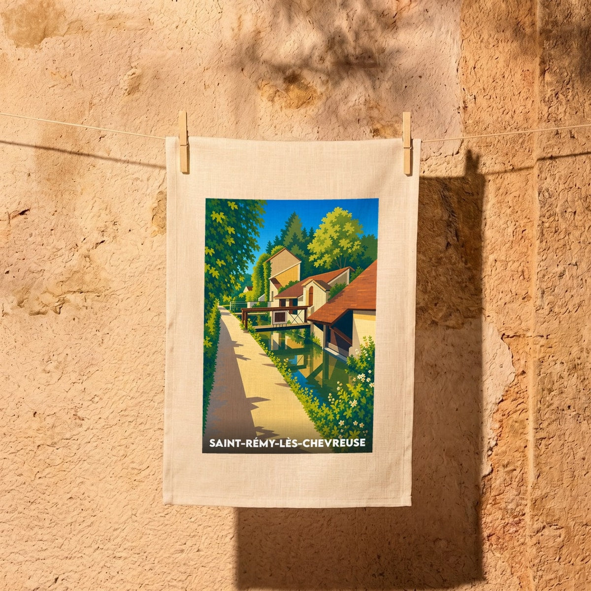 Torchon souvenir de la ville de Saint-Rémy-lès-Chevreuse avec une illustration stylisée d'un canal et de maisons anciennes.