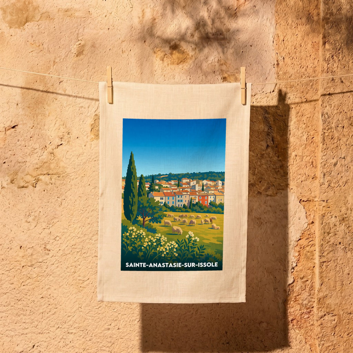 Torchon souvenir de la ville de Sainte-Anastasie-sur-Issole avec une illustration colorée d'un paysage provençal.