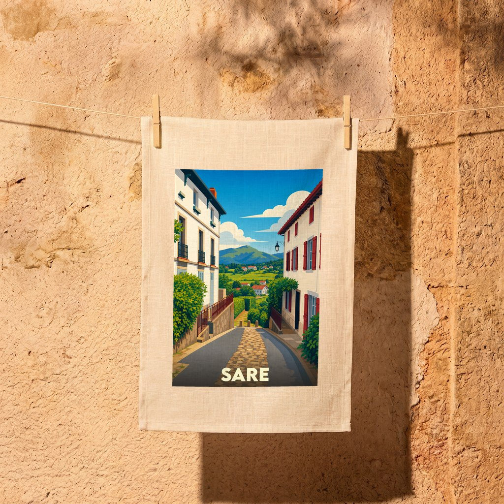 Torchon souvenir de la ville de Sare illustrant une rue pittoresque avec vue sur les montagnes.
