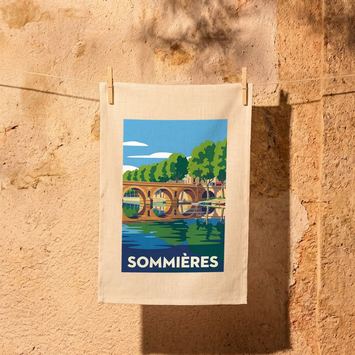 Torchon souvenir de la ville de Sommières avec une illustration stylisée de son pont et de la rivière.