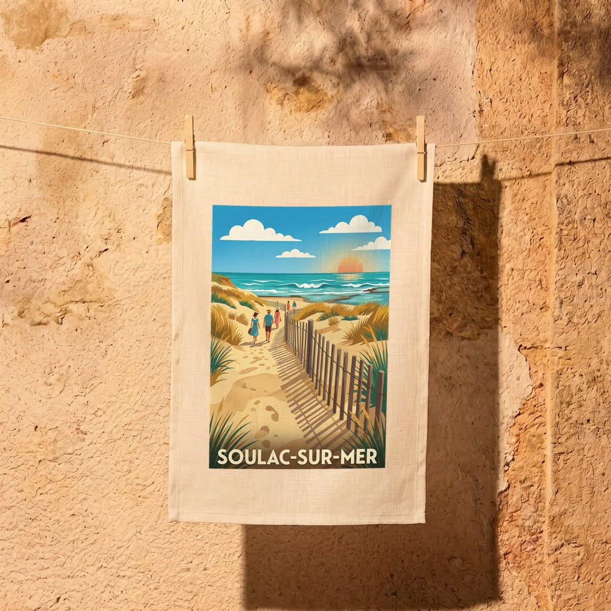 Torchon souvenir de la ville de Soulac-sur-Mer avec une illustration stylisée d'une plage au coucher du soleil.