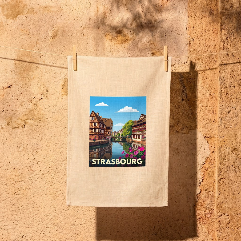 Torchon souvenir de la ville de Strasbourg avec une illustration stylisée de maisons à colombages au bord de l'eau.