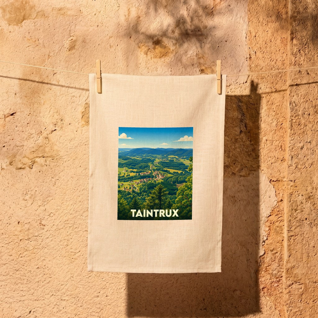 Torchon souvenir de la ville de Taintrux avec une illustration stylisée d'un paysage de montagne.