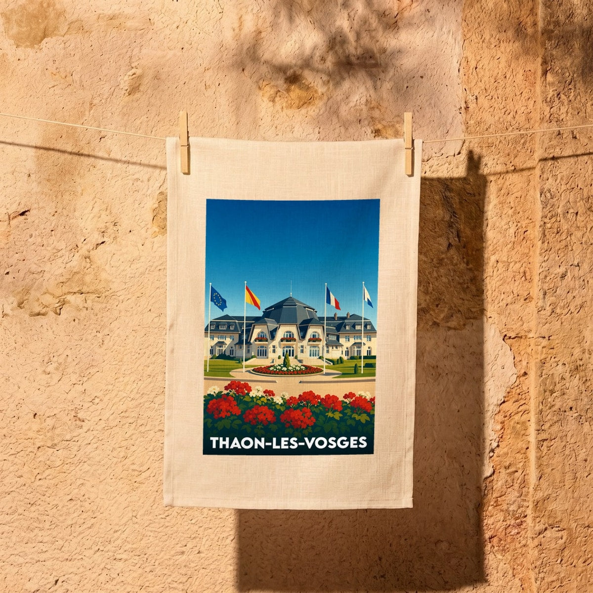 Torchon souvenir de la ville de Thaon-les-Vosges illustré par un bâtiment majestueux sous un ciel bleu.