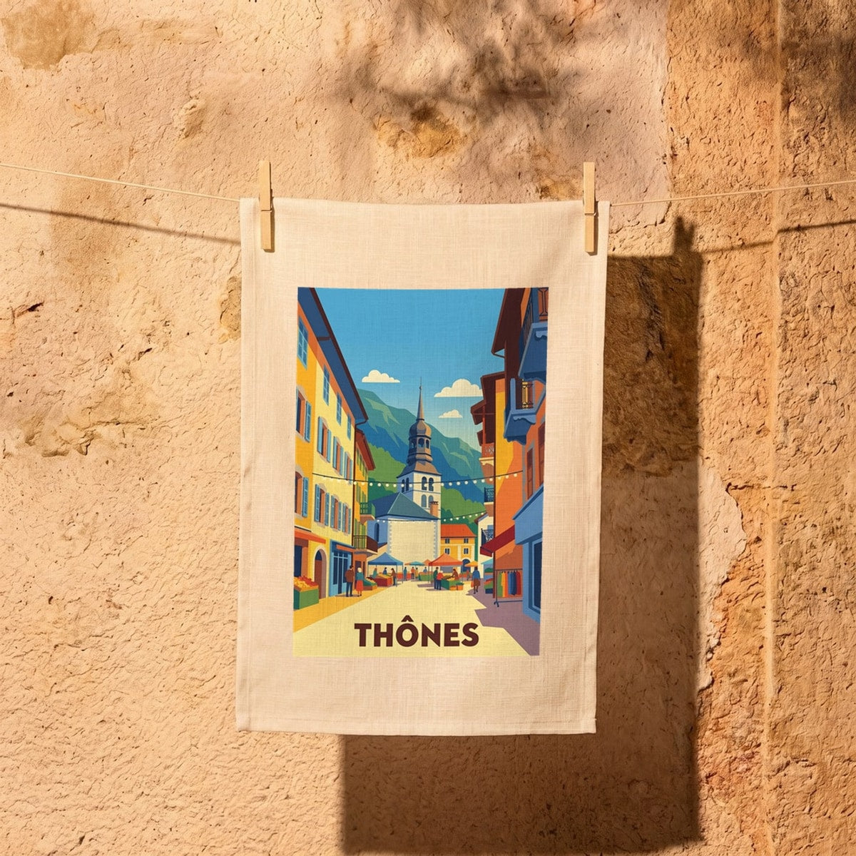 Torchon souvenir de la ville de Thônes avec une illustration stylisée de son marché coloré.