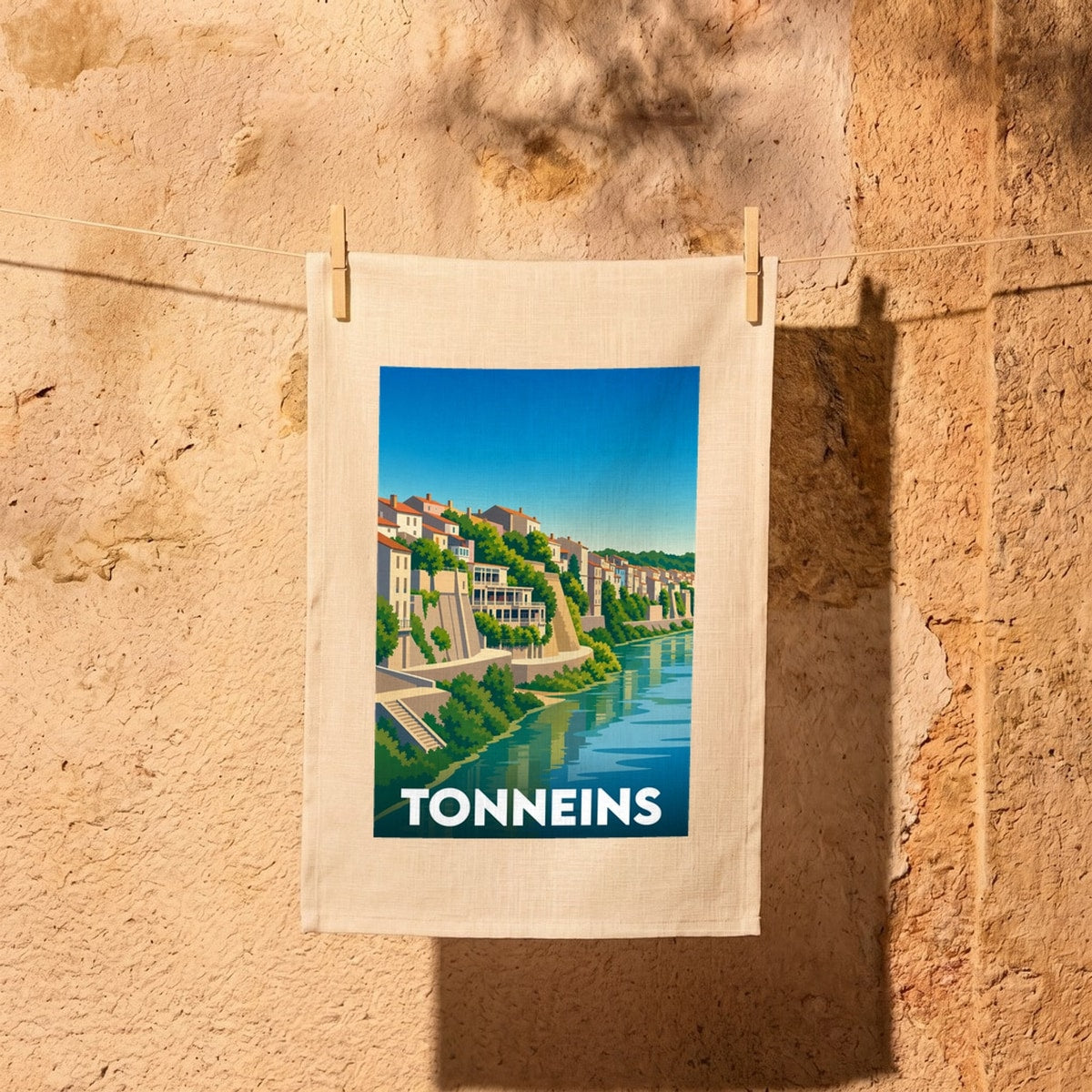 Torchon souvenir de la ville de Tonneins avec une illustration stylisée des quais du bord de l'eau.