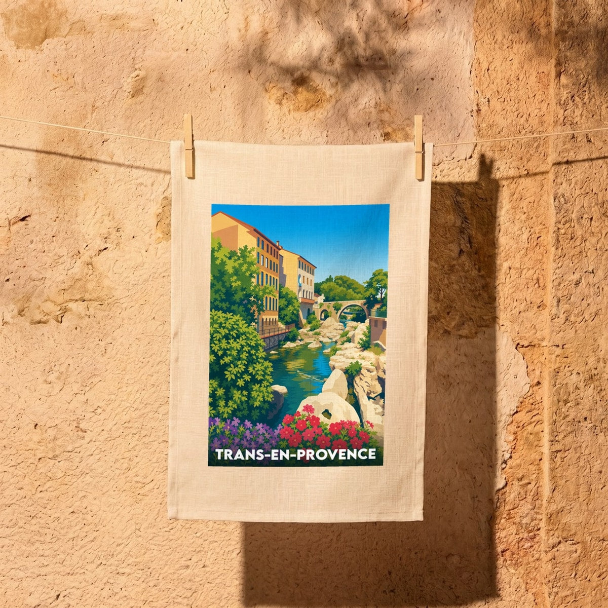 Torchon souvenir de la ville de Trans-en-Provence avec une illustration stylisée d'un pont en pierre enjambant une rivière.