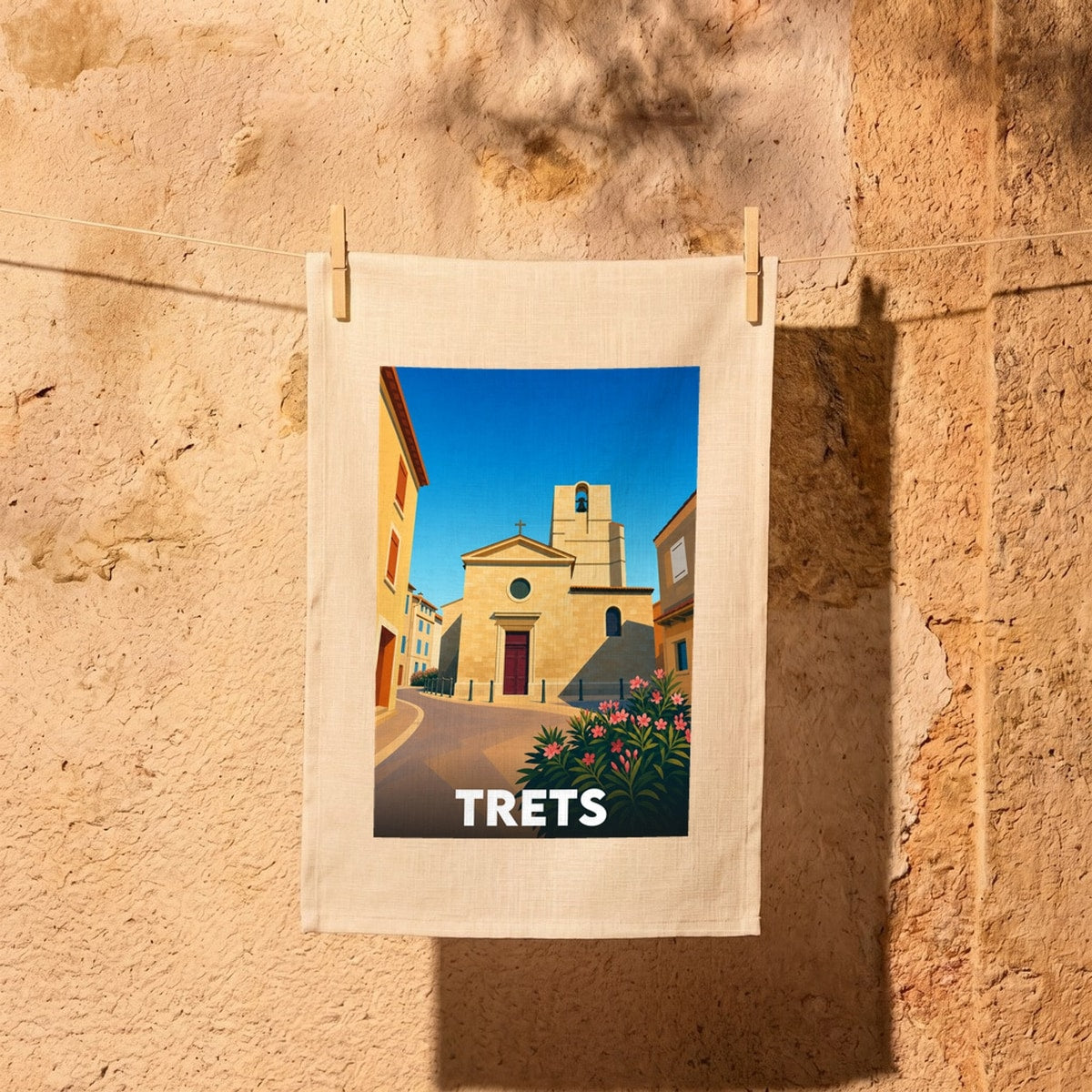 Torchon souvenir de la ville de Trets illustrant son église provençale sous un ciel bleu azur.