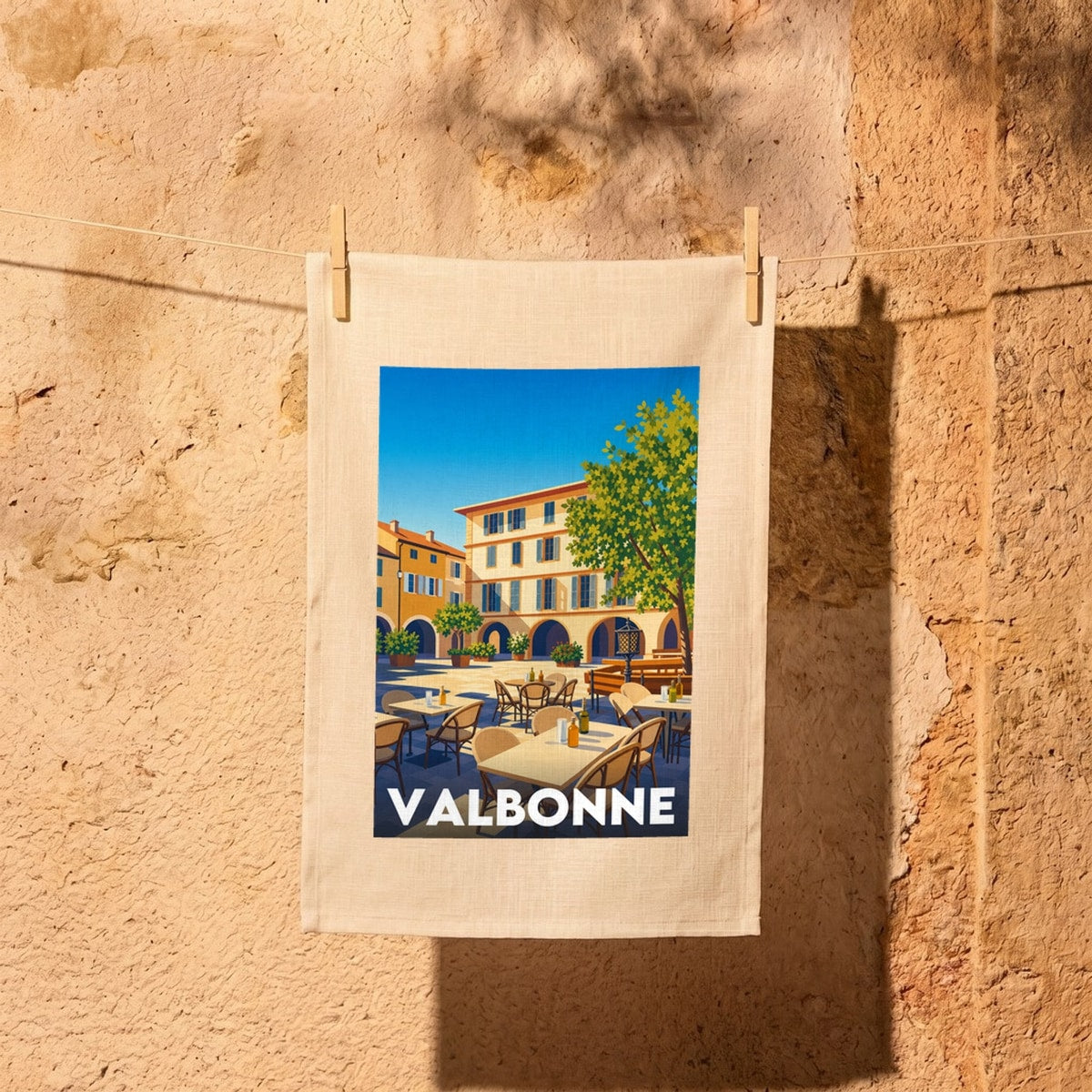 Torchon souvenir de la ville de Valbonne avec une illustration stylisée de sa place principale ensoleillée.