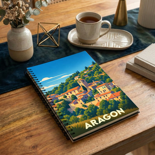 Carnet souvenir de la ville d'Aragon avec une illustration stylisée d'un village pittoresque niché dans les collines.
