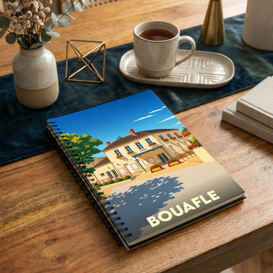 Carnet à spirale souvenir de la ville de Bouafle avec une illustration stylisée d'une maison de ville ensoleillée.
