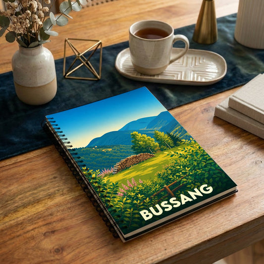 Carnet de notes souvenir de la ville de Bussang avec une illustration paysagère stylisée.