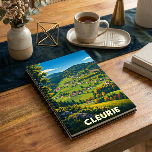 Carnet souvenir de la ville de Cleurie avec une illustration stylisée d'un paysage de montagne.