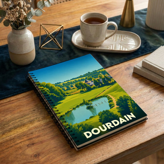 Carnet à spirales souvenir de la ville de Dourdain illustré par un paysage de campagne stylisé.