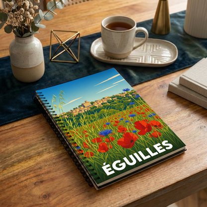Carnet souvenir de la ville d'Éguilles avec une illustration stylisée d'un champ de coquelicots devant le village.