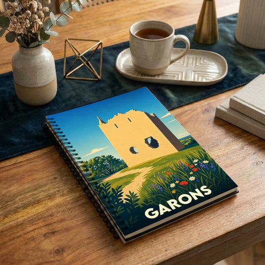 Carnet à spirales souvenir de la ville de Garons avec une illustration stylisée d'un bâtiment historique et d'un champ fleuri.