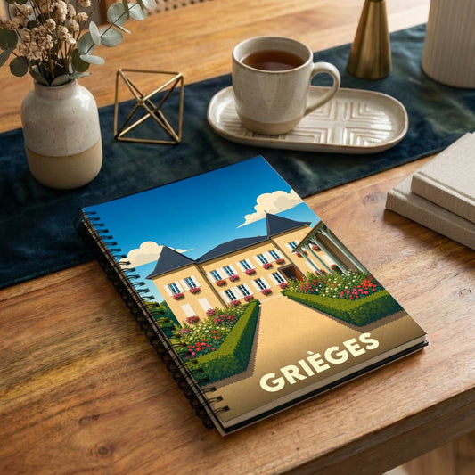 Carnet de notes à spirales souvenir de la ville de Grièges avec une illustration stylisée d'une demeure fleurie.