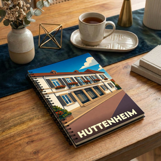 Carnet à spirales souvenir de la ville de Huttenheim avec une illustration stylisée d'un bâtiment traditionnel alsacien.