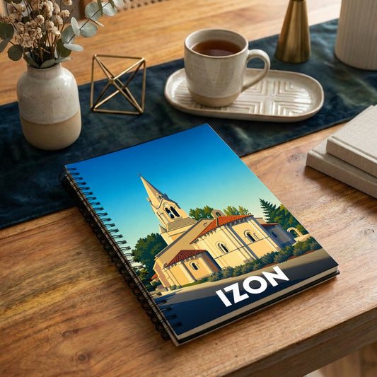 Carnet à spirales souvenir de la ville d'Izon avec une illustration stylisée de son église sous un ciel bleu.