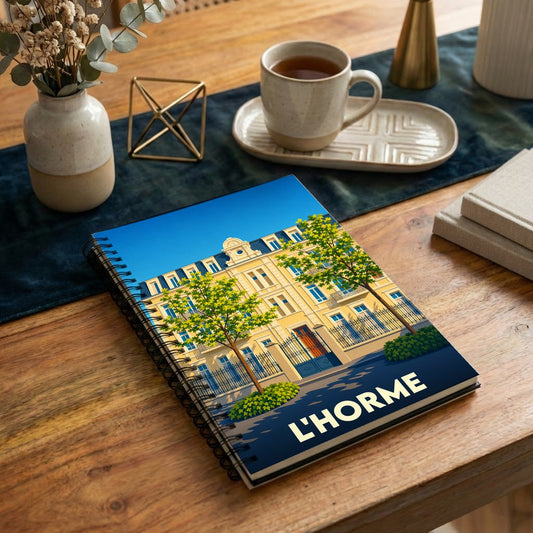 Carnet à spirales souvenir de la ville de L'Horme avec une illustration stylisée d'un bâtiment historique.