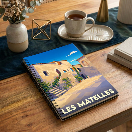 Carnet à spirales souvenir de la ville de Les Matelles avec une illustration stylisée de ses ruelles ensoleillées.