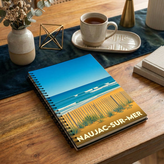 Carnet à spirales souvenir de Naujac-sur-Mer avec une illustration stylisée d'une plage et de ses dunes.