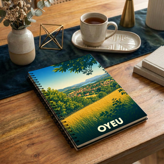 Carnet à spirales souvenir de la ville d'Oyeu avec une illustration stylisée de paysages vallonnés.