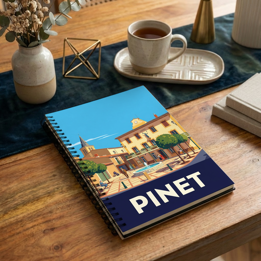 Carnet souvenir de la ville de Pinet avec une illustration stylisée de sa place centrale.