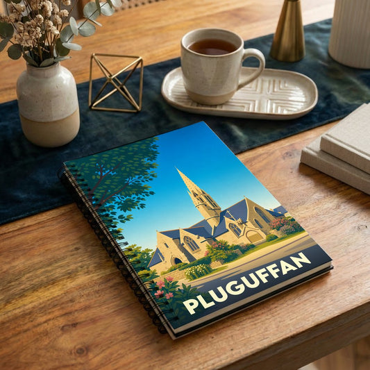 Carnet à spirales souvenir de la ville de Pluguffan illustré par un dessin stylisé de son église sous un ciel bleu.
