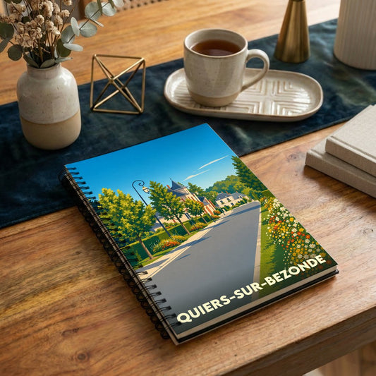 Carnet à spirales souvenir de la ville de Quiers-sur-Bezonde avec une illustration stylisée d'une rue ensoleillée.
