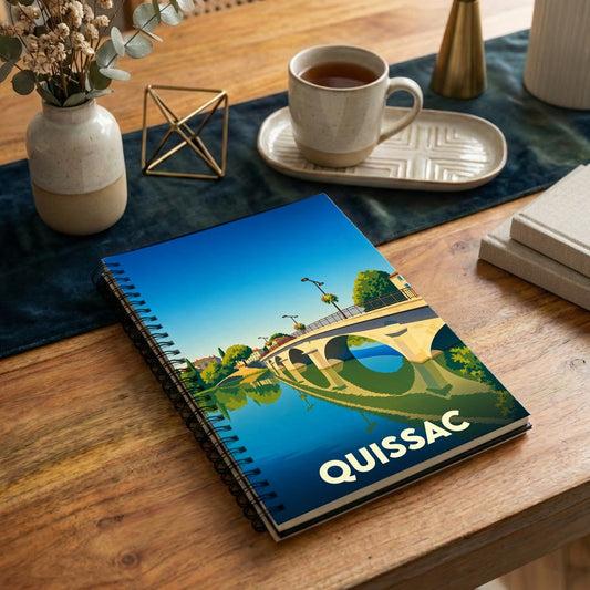 Carnet à spirale souvenir de la ville de Quissac avec une illustration stylisée de son pont.